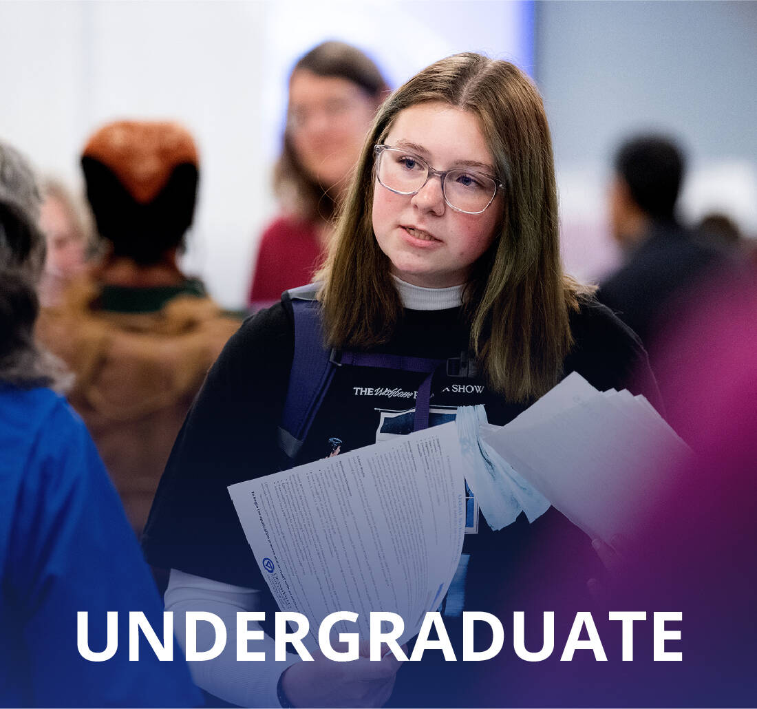 GVSU student holding papers and speaking with someone at orientation